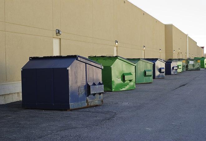 a row of yellow and blue dumpsters at a construction site in Fairfield, AL